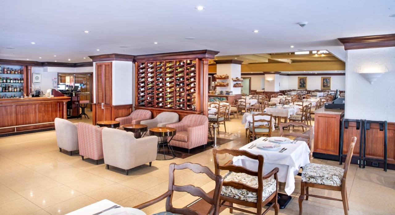 Torre Monserrate Bogota Exterior photo The photo shows the interior of a restaurant. It features a spacious dining area with various tables and chairs arranged throughout. Some tables are set with white tablecloths, indicating a formal dining setup. In one section, there are cozy armchair