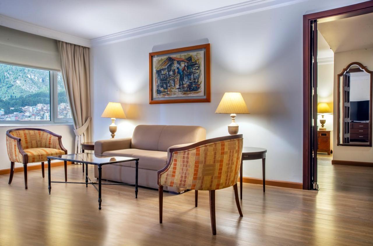 Torre Monserrate Bogota Exterior photo The photo shows a well-decorated living room. It features a light-colored sofa in the center, flanked by two armchairs with a striped design. A glass coffee table sits in front of the sofa. On either side of the room, there are lamps on the side tabl