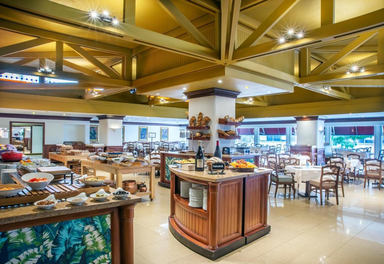 Torre Monserrate Bogota Exterior photo The photo shows an inviting restaurant interior featuring a spacious dining area. The ceiling has a distinctive design with wooden beams, enhancing the aesthetic. In the foreground, there is a buffet area with a variety of food options displayed. The