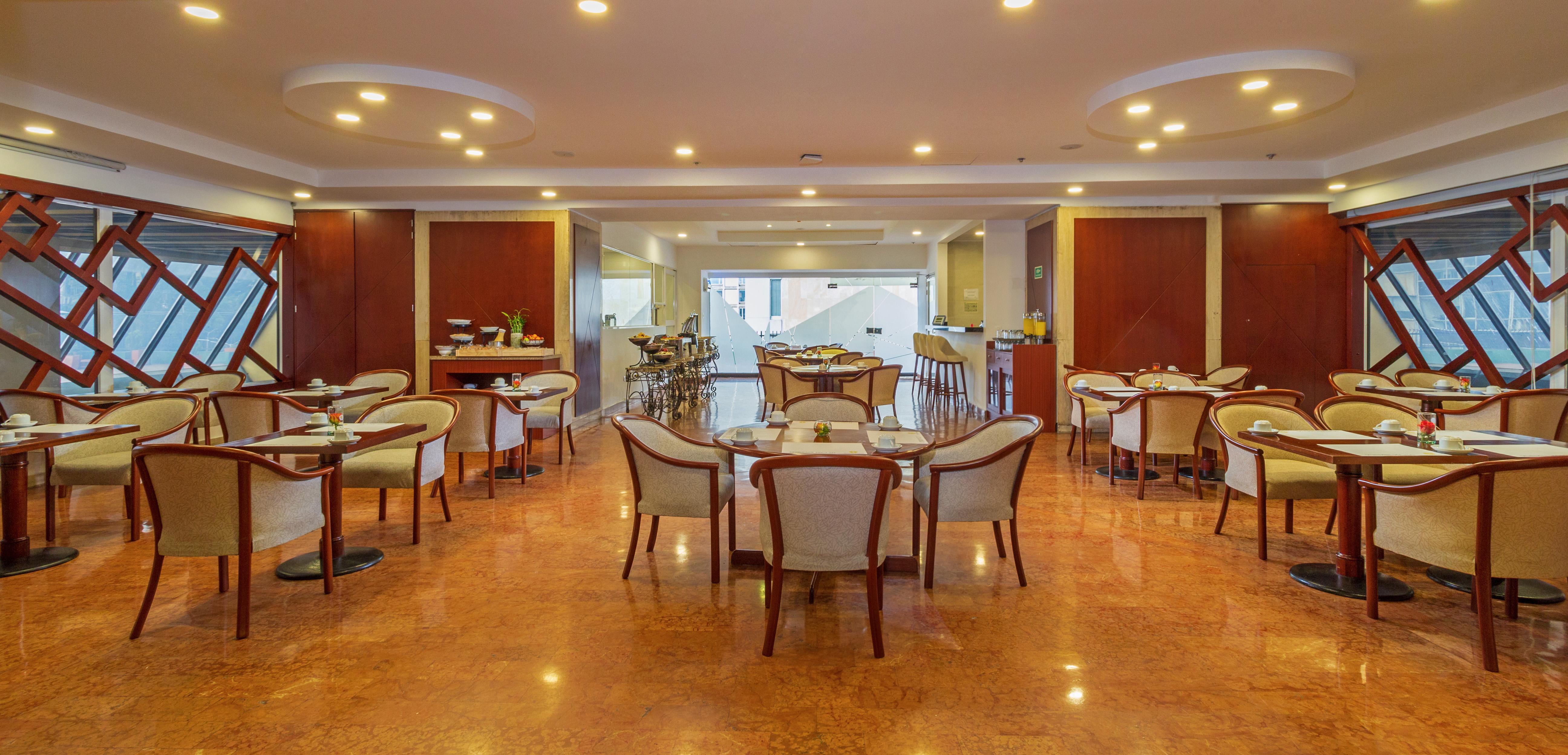 Torre Monserrate Bogota Exterior photo The photo displays an elegant dining area in a restaurant. The interior features smooth, polished flooring and soft lighting. There are several round tables surrounded by cushioned chairs, creating a cozy and inviting atmosphere. The space appears we