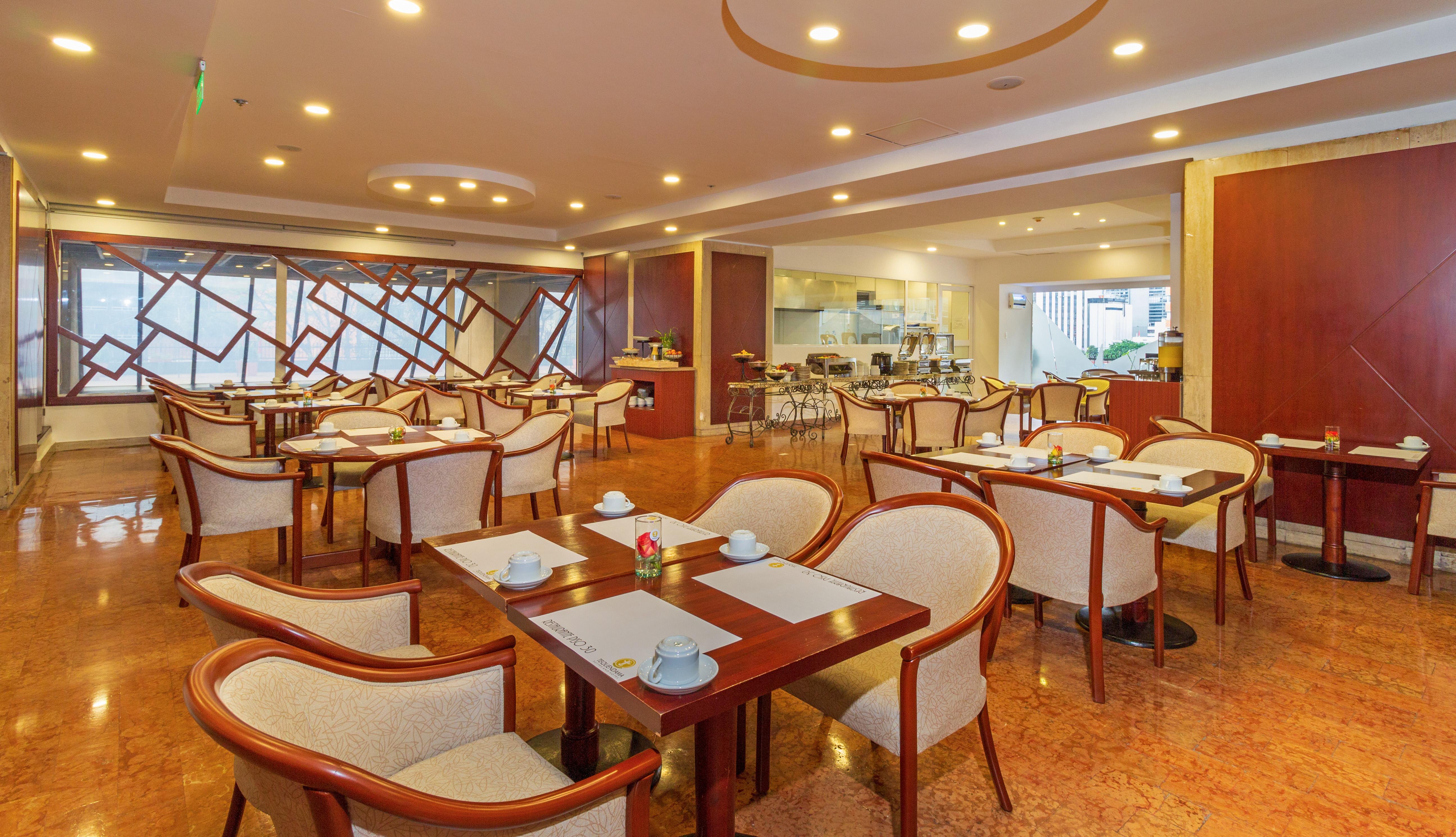 Torre Monserrate Bogota Exterior photo The photo shows a dining area, likely a restaurant or café. The space features neatly arranged tables with beige and wooden chairs. Each table has a setting that includes small plates, cups, and a decorative flower centerpiece. The interior design is