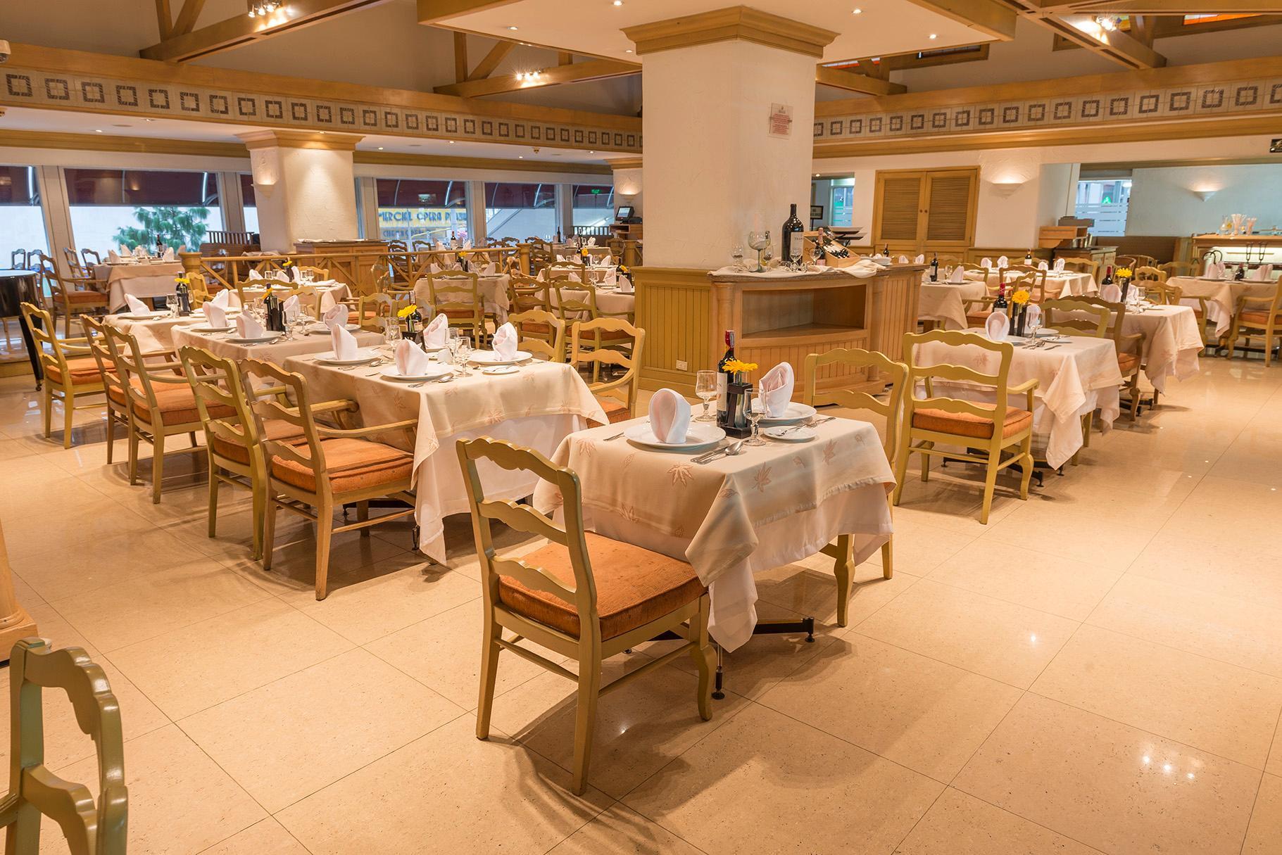 Torre Monserrate Bogota Exterior photo The photo depicts a dining area of a restaurant. The space is furnished with multiple tables, each set with tablecloths and arranged neatly. The chairs are wooden with padded seating, and there are plates, napkins, and utensils prepared for diners. T